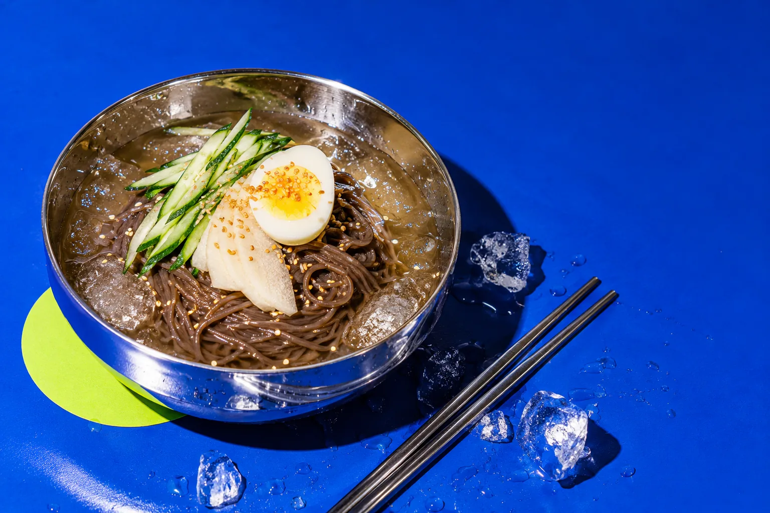 코발트 배경 위 금속 그릇에 담긴 냉면 화보